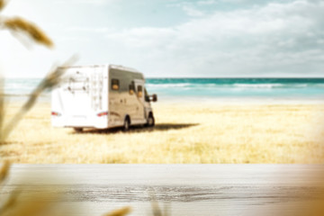 Table background with a beautiful beach ocean view. Sunny beach in distance. A camper on a beach....