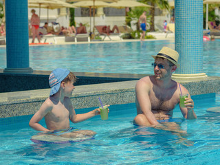 Dad and son spending time together inside pool bar on summer vacation.