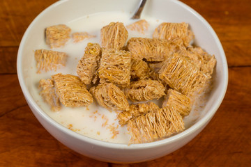 Overhead View of Bowl of Shreaded Wheat on Rustic Table with Honey added  as Sweetener.