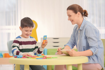 Female psychologist working with boy suffering from autistic disorder