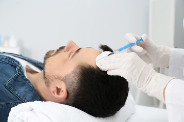 Obraz na płótnie Canvas Man with hair loss problem receiving injection in salon