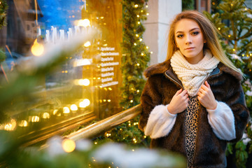Fototapeta na wymiar beautiful young woman standing near the window on the street in winter, festive mood