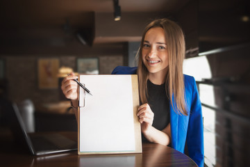 A beautiful woman with long hair is holding a banner, a sheet of paper and smiling, a place for text.