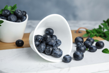 Board with bowl of tasty fresh blueberries on table