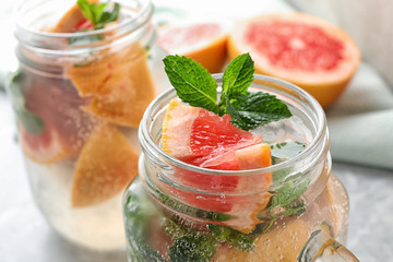 Mason jar of refreshing drink with grapefruit and mint on table, closeup view. Space for text