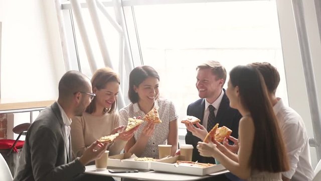 Cheerful diverse team people company workers laughing eating pizza together