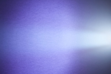 Cone-shaped light ray of light on a purple textural and half-blurred background