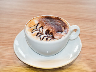 a cappuccino in a white cup with milk foam and a pattern in the form of a sheet