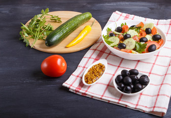 Vegetarian salad of tomatoes, cucumbers, parsley, olives and mustard on linen tablecloth.
