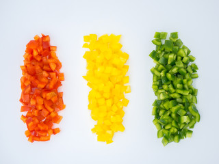 Red, green and yellow sweet bell peppers chopped on white background