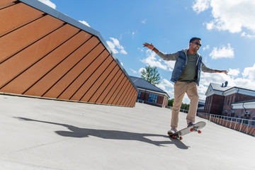 people and leisure concept - smiling indian man doing trick on skateboard on roof top © Syda Productions