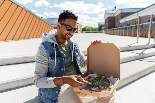 Leisure And Fast Food Concept - Indian Man Eating Takeaway Pizza On Roof Top