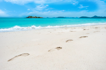 Fototapeta na wymiar Footprints on sand beach and wave