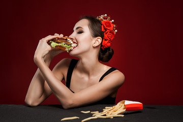 Glamour beautiful sexy woman eating burger over red backround.