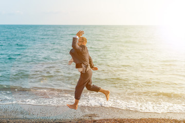 Happy businessman jumping on the beach. Man having fun by the sea. Summer vacation and travel concept