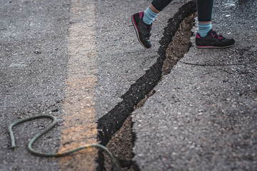 Girl jumping over the crack gap in the road