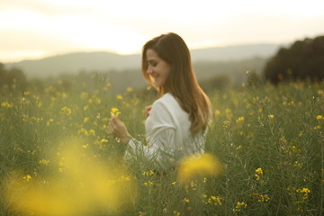 Fototapeta na wymiar Beautiful woman on yellow flowers field with dark cloudy sky