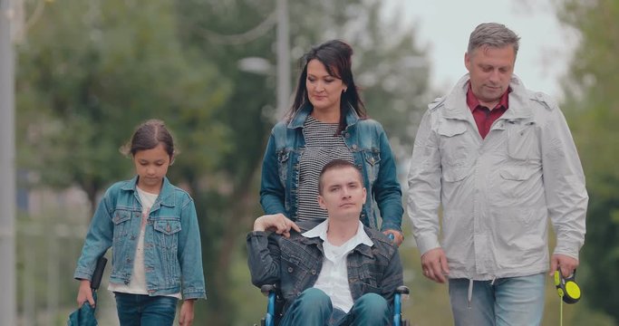 Disabled young man on a walk with his family. Portrait view.