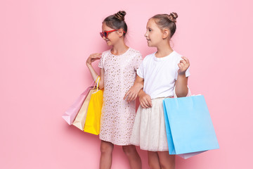 Two smiling teenage girls hold bags in their hands after a shopping trip