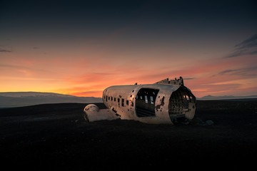 Airplane wreck on a black beach at the sunset. Iceland