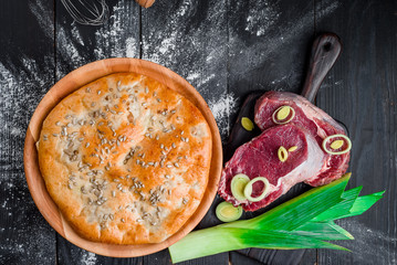 Round homemade meat pie on a black wooden background in a beautiful composition. top view. Space. Close-up