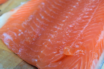 Fresh raw salmon on wooden cutting board. Shallow depth of field.