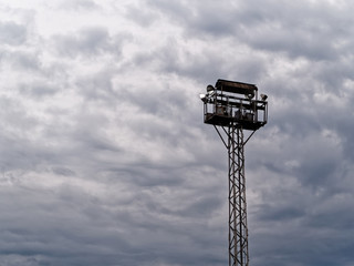 Observation security tower with spotlights against a dark evening cloudy stormy sky