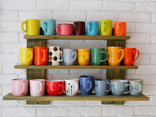 Set of multicolored coffee cups on a shelf on the white brick wall in cozy city cafe