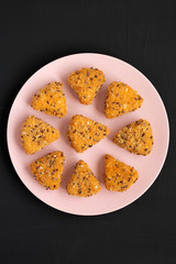 Fried camembert on a pink plate on a black background, top view. Flat lay, overhead, from above. Close-up.