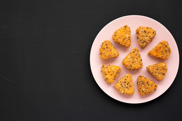 Top view, fried camembert on a pink plate on a black background. Flat lay, overhead, from above. Copy space.