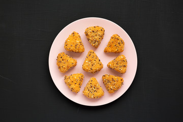 Fried camembert on a pink plate on a black surface, top view. Flat lay, overhead, from above. Close-up.