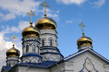 Fototapeta na wymiar Orthodox Christian Cathedral with golden domes and crosses against the sky, spring day. Sobor Tikhvinskoy Ikony Bozhiyey Materi, Tsivilsk, Russia