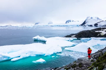 Fotobehang Tourist taking photos of amazing frozen landscape in Antarctica with icebergs, snow, mountains and glaciers, beautiful nature in Antarctic Peninsula with ice © NicoElNino