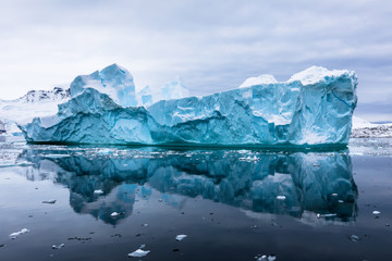 Impressive iceberg with blue ice and beautiful reflection on water in Antarctica, scenic landscape in Antarctic Peninsula