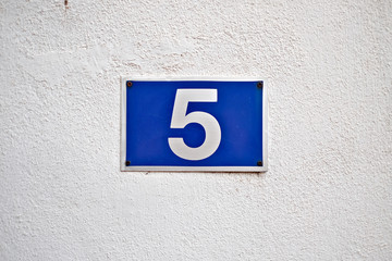 Number five ( 5 ), blue plate on a white surface.