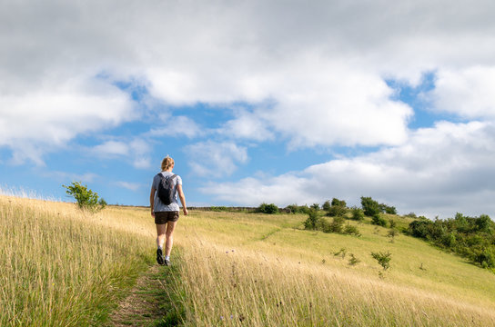 Woman hiking on a field on the Cotswold Way, Gloucestershire, England