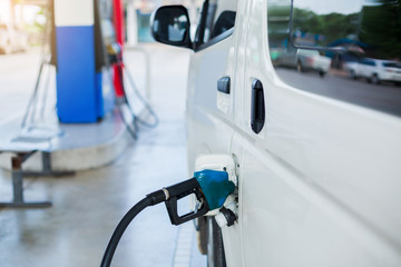 Hand refilling the white van with fuel at the gas station. Oil and gas energy.