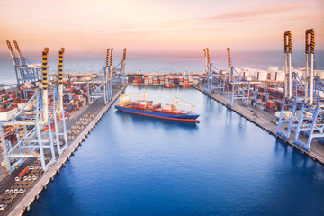 Large container ship leaves cargo port at sea, sunset. Aerial top view