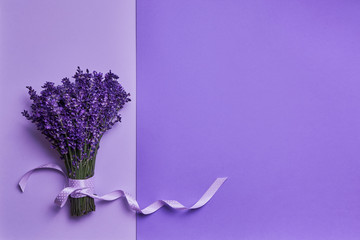 Bunch of fresh lavender decorated with ribbon on purple background. Violet flowers. Greeting floral...