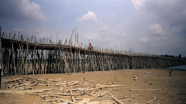 Projet motorbike crossing a bamboo bridge over a riverbed 