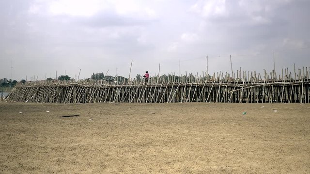 Projet motorbike crossing a bamboo bridge over a riverbed 