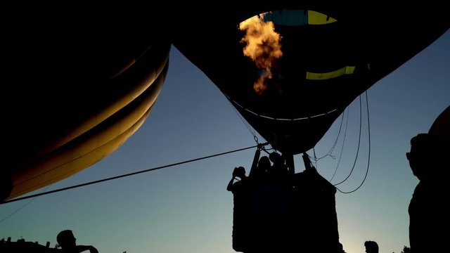 Hot air balloon celebration in Spanish town Igualada. International meeting of hot air balloons and flying competition. Dark silhouette of people in a hot air balloon basket