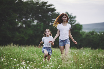mother and daughter running on meadow