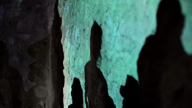 Silhouettes of dancing people on a stone wall. Colourful lighting of a venue, moving shadows of people. Party night, creative background, motion. Dancing people during a concert