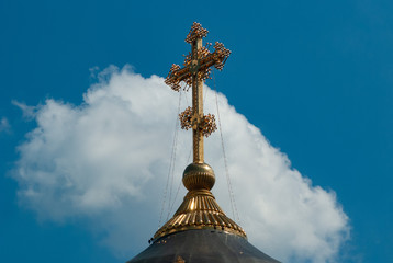 Fototapeta na wymiar The Golden cross of the Church against the blue sky with clouds, the Central composition,