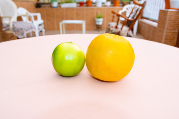 A green lemon and an orange close up with a colorful background