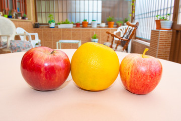Red apples and an orange in row