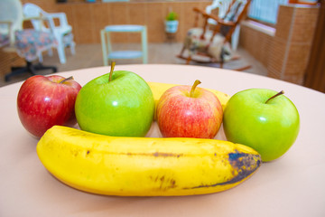 Colorful red and green apples next to a banana