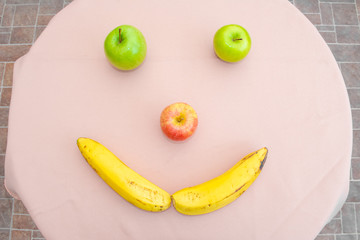 Happy face formed with fruits. Apples and banana forming a face. Happiness.