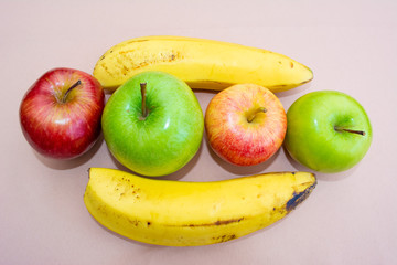Green and red apples with bananas on the table